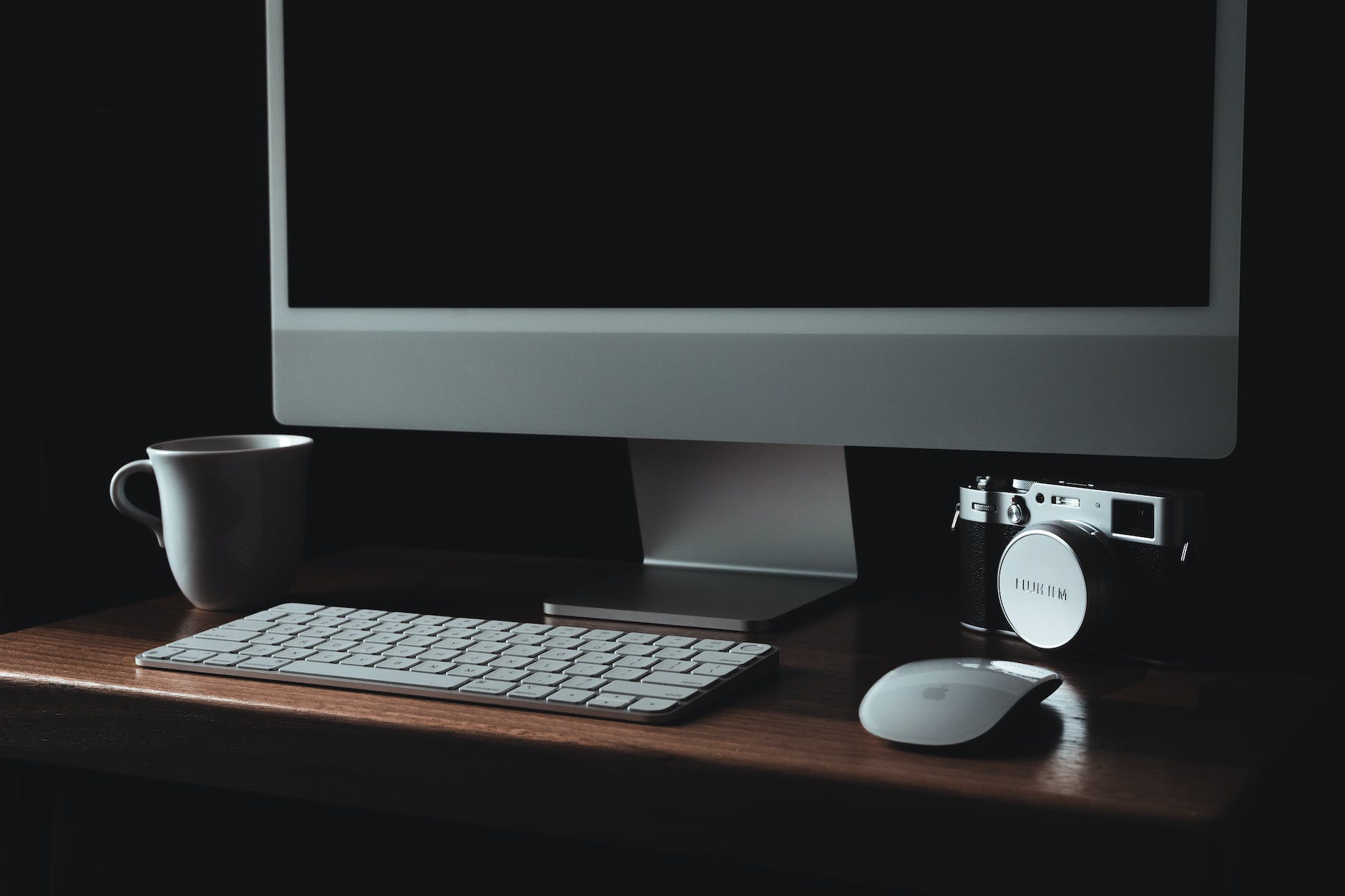 a computer and a camera on a wooden table